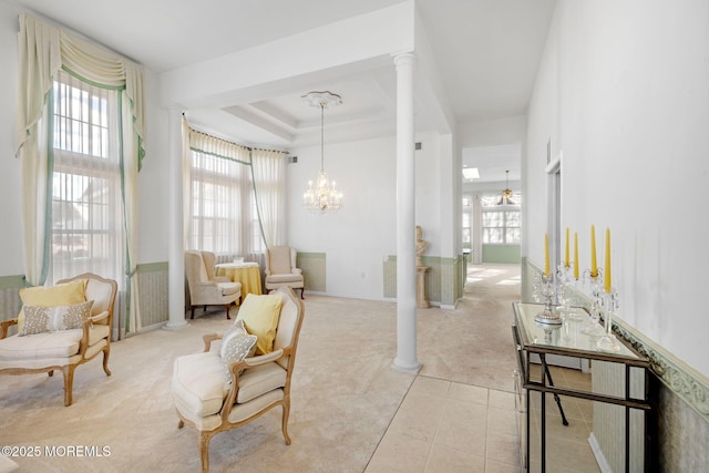 sitting room with a raised ceiling, decorative columns, light carpet, and a wealth of natural light