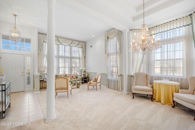 entryway with decorative columns, a high ceiling, tile patterned flooring, a tray ceiling, and an inviting chandelier