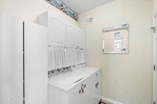 laundry area featuring washer and clothes dryer and cabinets