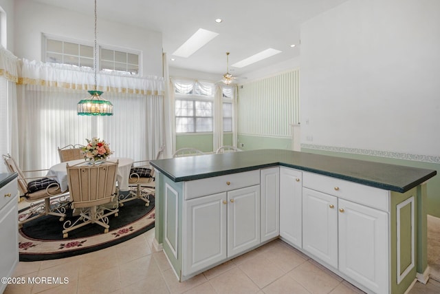 kitchen featuring white cabinetry, pendant lighting, light tile patterned floors, and a skylight