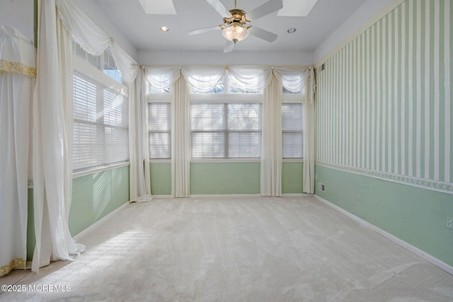 unfurnished sunroom featuring a wealth of natural light, ceiling fan, and a skylight