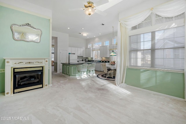 unfurnished living room featuring light colored carpet and ceiling fan