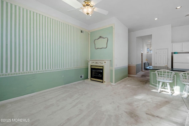 unfurnished living room featuring light carpet and ceiling fan