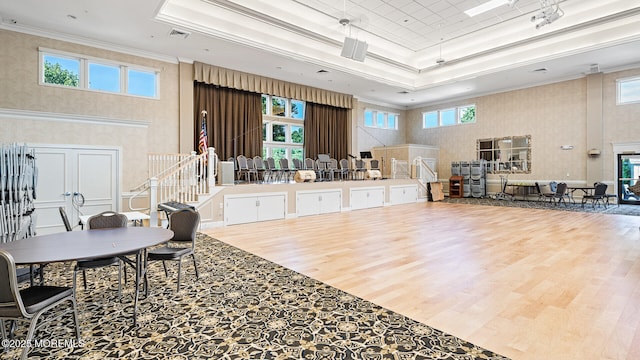 interior space with hardwood / wood-style flooring, ornamental molding, a raised ceiling, and a high ceiling