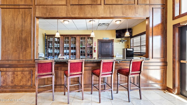 bar with pendant lighting, light tile patterned floors, and a drop ceiling