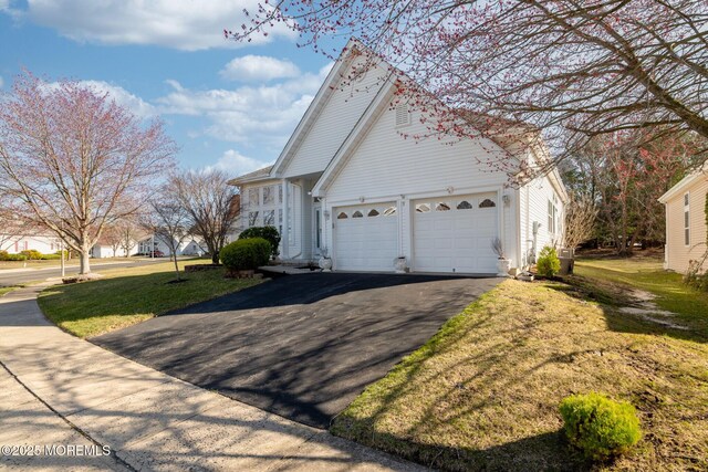 view of front of property featuring aphalt driveway, an attached garage, and a front lawn