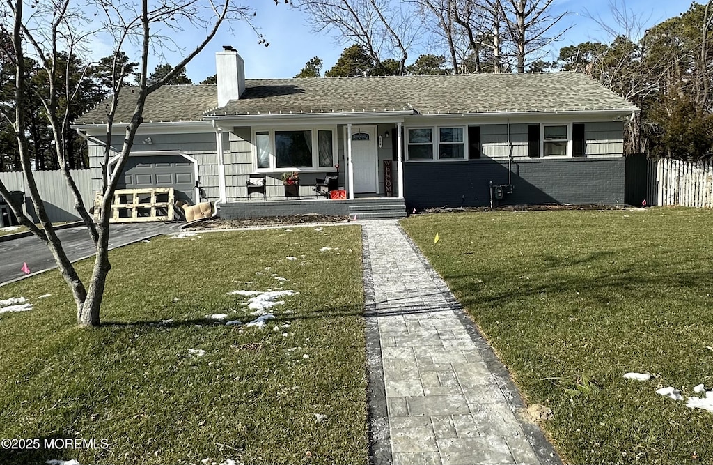 ranch-style home featuring a chimney, a porch, a front yard, fence, and a garage