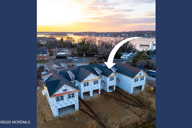 aerial view at dusk featuring a water view