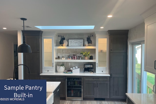 kitchen featuring tasteful backsplash, beverage cooler, light wood-type flooring, and a skylight