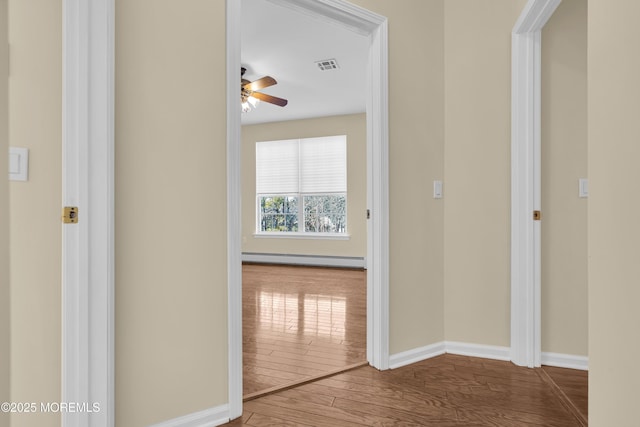 hallway featuring a baseboard heating unit and hardwood / wood-style flooring