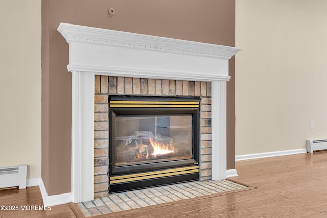 details with wood-type flooring, a brick fireplace, and a baseboard heating unit