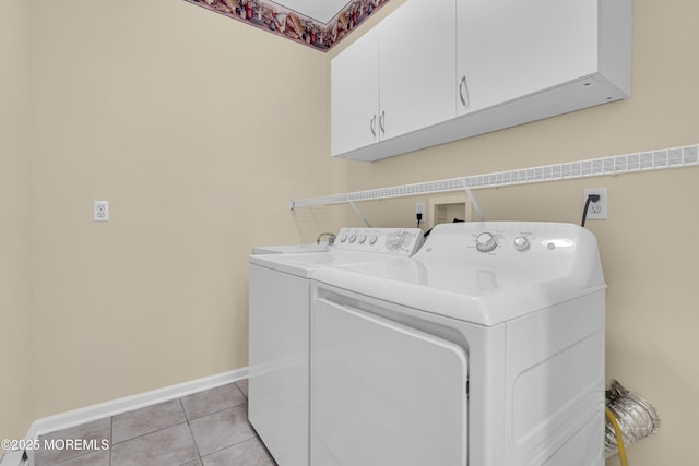 washroom with independent washer and dryer, light tile patterned floors, and cabinets