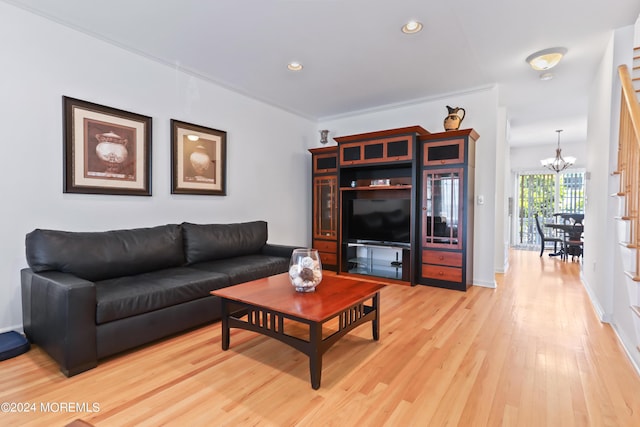 living room featuring crown molding, an inviting chandelier, and light hardwood / wood-style floors