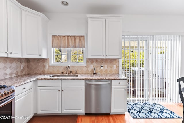 kitchen featuring stainless steel appliances, white cabinetry, sink, and light stone counters