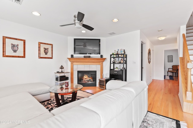 living room featuring ceiling fan, a fireplace, and light wood-type flooring