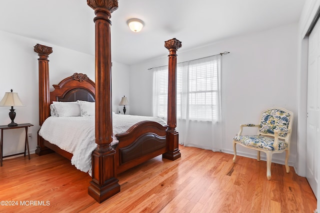 bedroom with light hardwood / wood-style flooring, decorative columns, and a closet