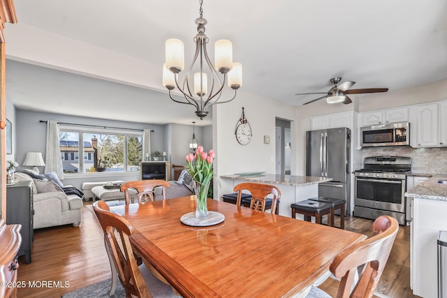 dining space featuring ceiling fan with notable chandelier and dark hardwood / wood-style floors