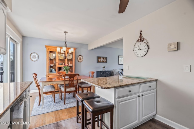 kitchen with a breakfast bar, dark stone countertops, dark hardwood / wood-style floors, white cabinets, and kitchen peninsula