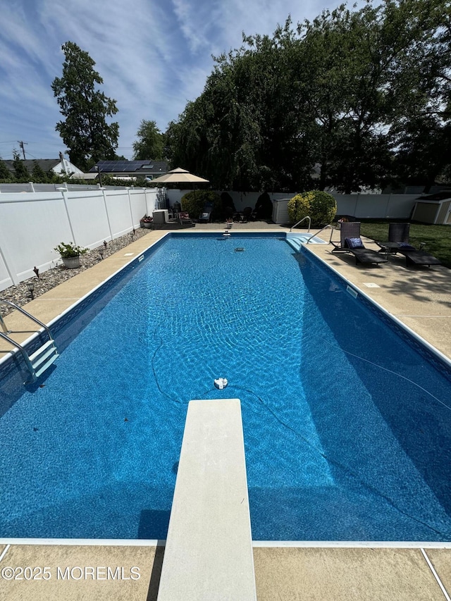 view of pool featuring a diving board and a patio area