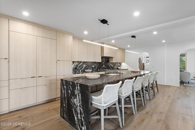 402 Fifth Ave, Asbury Park, NJ 07712 - kitchen featuring modern cabinets, arched walkways, a large island with sink, dark stone countertops, and a kitchen breakfast bar