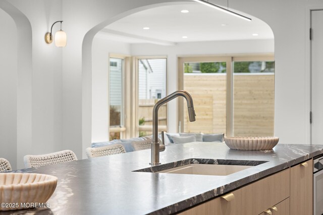 402 Fifth Ave, Asbury Park, NJ 07712 - kitchen with a sink, arched walkways, dark countertops, light brown cabinetry, and recessed lighting