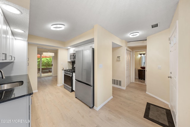 90 Van Liew Ct, East Brunswick, NJ 08816 - kitchen featuring stainless steel appliances, white cabinets, light wood-type flooring, and a textured ceiling