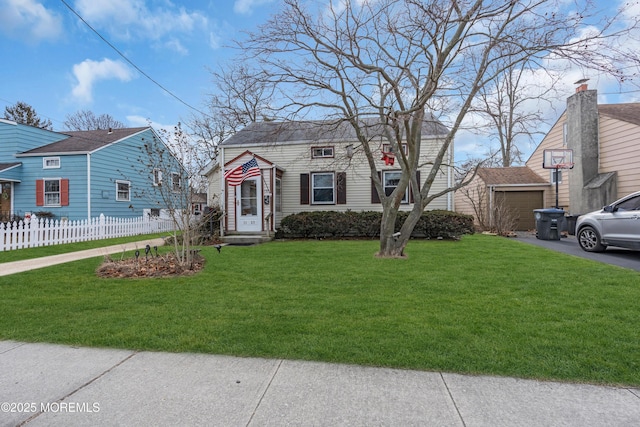 view of front of house with an outbuilding, aphalt driveway, a garage, fence, and a front yard