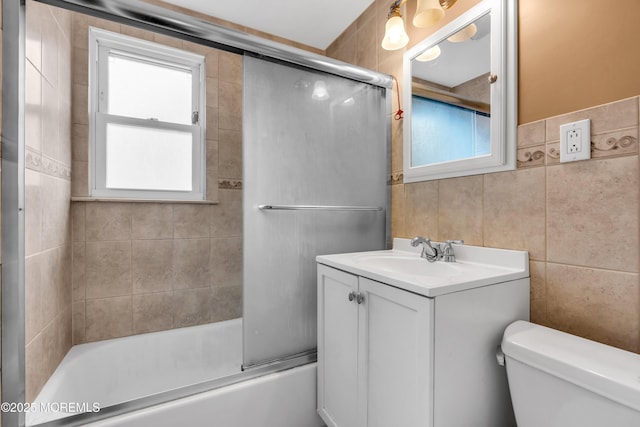 bathroom featuring toilet, plenty of natural light, tile walls, and vanity