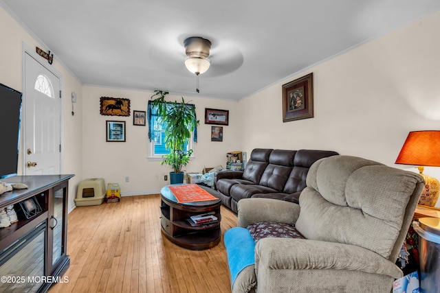 living area with light wood-style floors, crown molding, ceiling fan, and baseboards