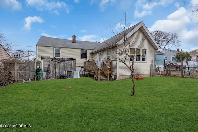 back of house with a fenced backyard, a yard, a wooden deck, a gate, and a chimney