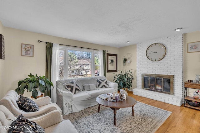 living room with a brick fireplace, hardwood / wood-style floors, and a textured ceiling