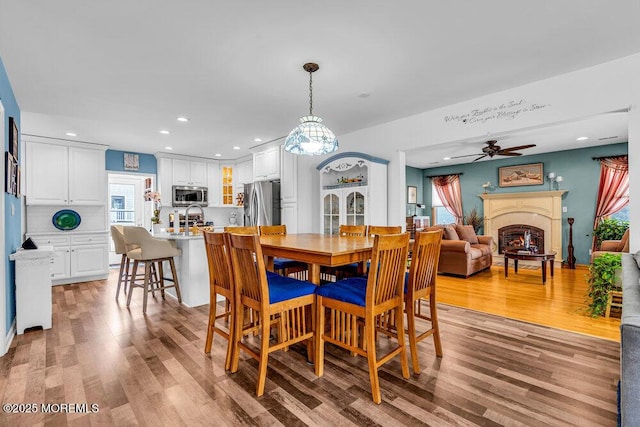 dining area featuring ceiling fan, sink, and light wood-type flooring