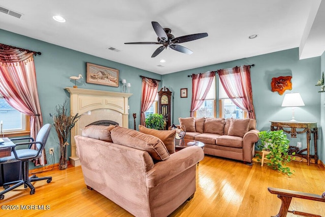 living room featuring ceiling fan, a wealth of natural light, and light wood-type flooring