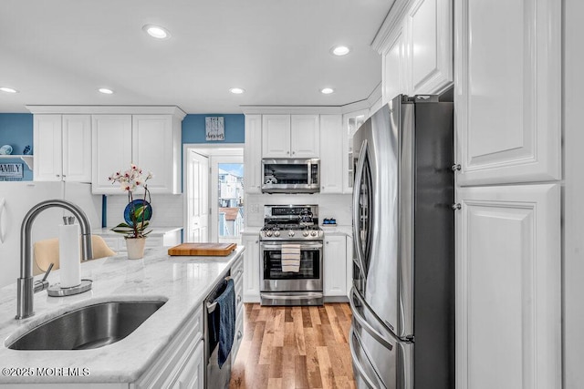 kitchen featuring light stone counters, sink, stainless steel appliances, and white cabinets