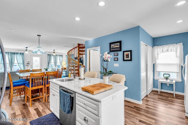 kitchen featuring sink, a center island with sink, stainless steel dishwasher, pendant lighting, and white cabinets