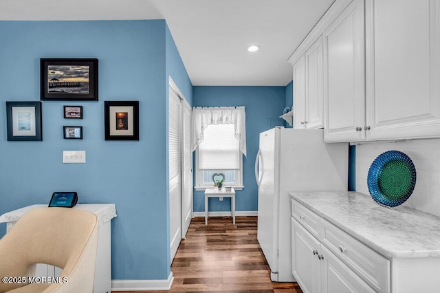 kitchen featuring dark wood-type flooring, white refrigerator, decorative backsplash, and white cabinets