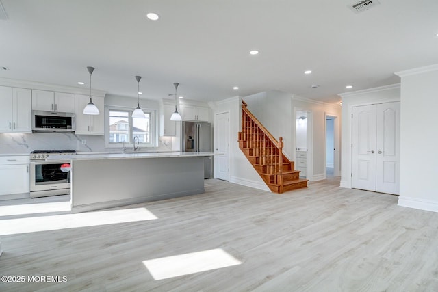 kitchen featuring pendant lighting, backsplash, stainless steel appliances, a center island, and white cabinets