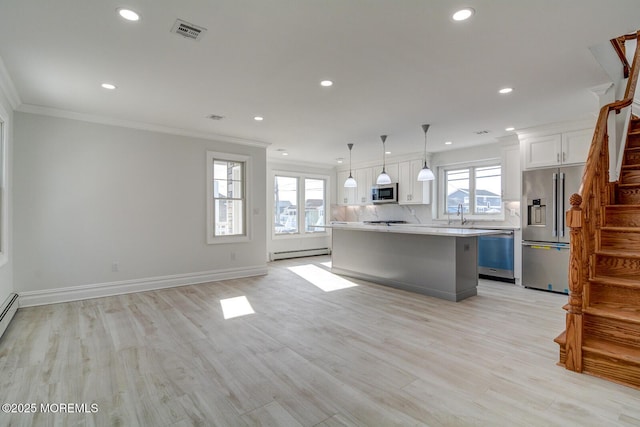 kitchen featuring pendant lighting, appliances with stainless steel finishes, white cabinetry, a baseboard heating unit, and a kitchen island