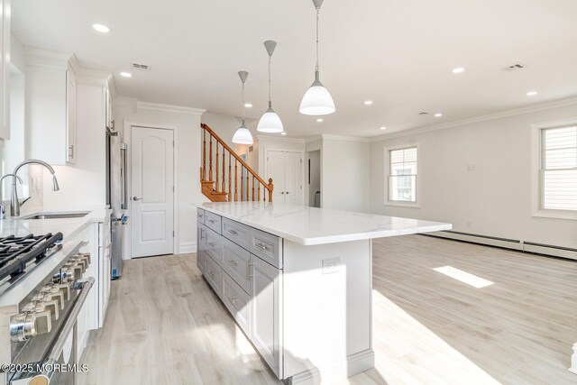 kitchen with sink, hanging light fixtures, stainless steel refrigerator, a kitchen island, and white cabinets