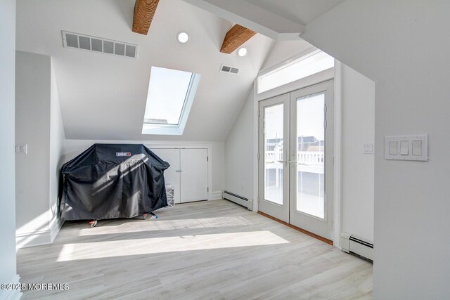 additional living space with french doors, a baseboard radiator, lofted ceiling with skylight, and light hardwood / wood-style flooring