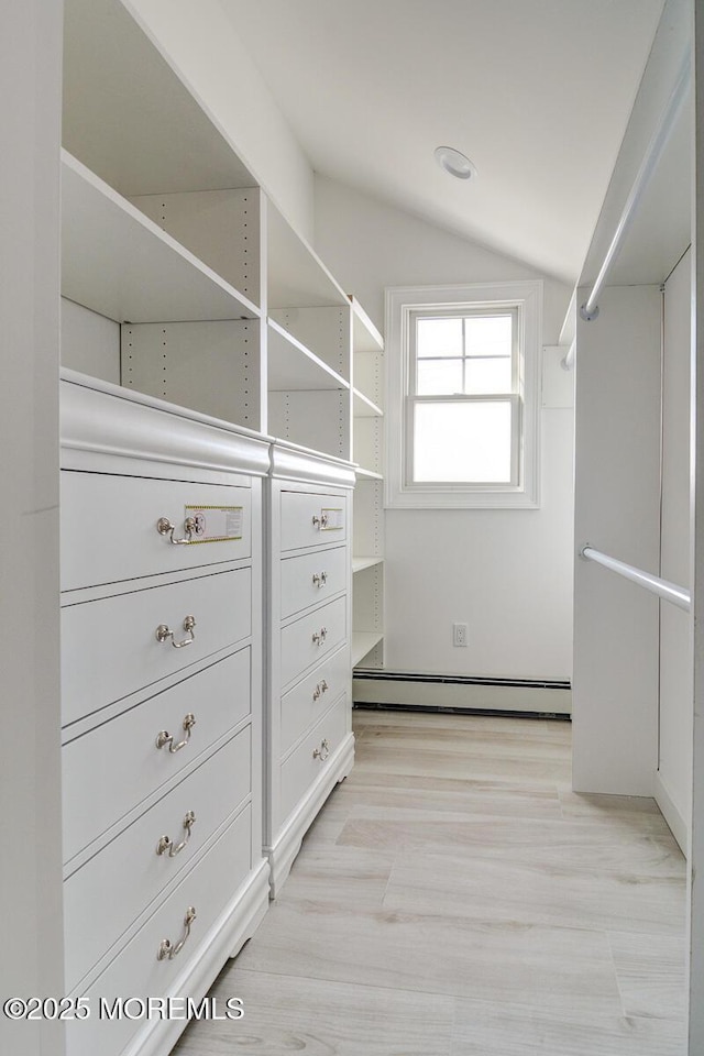 walk in closet featuring lofted ceiling, a baseboard heating unit, and light hardwood / wood-style flooring