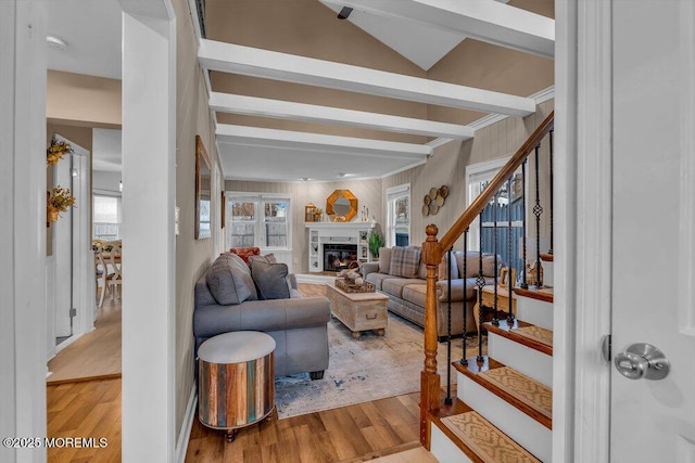 living room with beam ceiling, a wealth of natural light, and light hardwood / wood-style floors