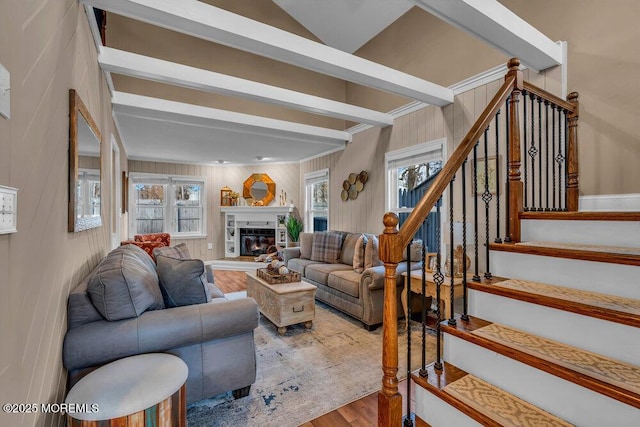 living room with wooden walls, plenty of natural light, beam ceiling, and hardwood / wood-style floors