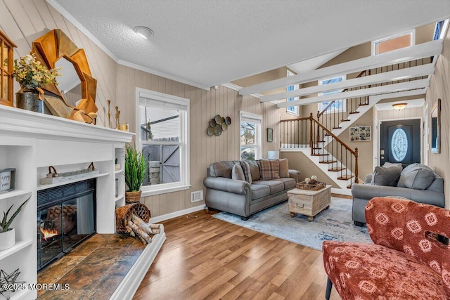 living room with hardwood / wood-style flooring, a fireplace, a textured ceiling, and crown molding