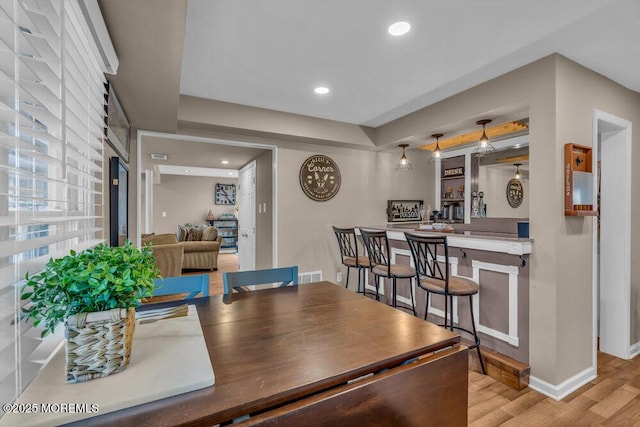 dining space with bar area and light wood-type flooring