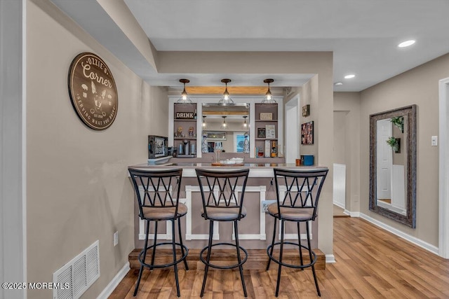 bar with pendant lighting and hardwood / wood-style flooring