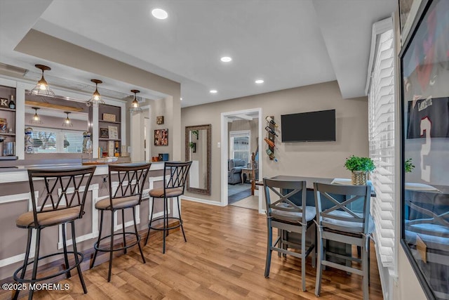 kitchen with light hardwood / wood-style flooring, a kitchen breakfast bar, and decorative light fixtures