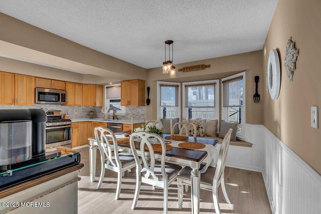 dining room with sink, a textured ceiling, and light hardwood / wood-style floors