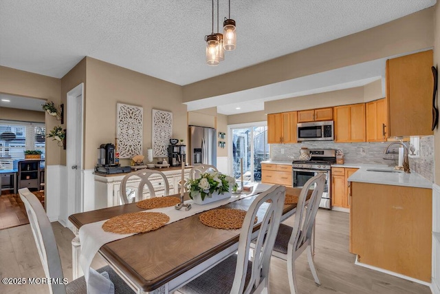 dining space featuring sink, light hardwood / wood-style flooring, and a textured ceiling