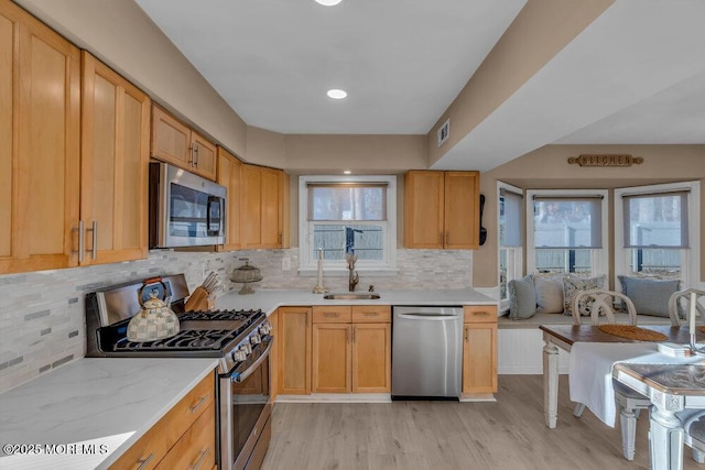 kitchen with sink, light hardwood / wood-style flooring, appliances with stainless steel finishes, backsplash, and light brown cabinets